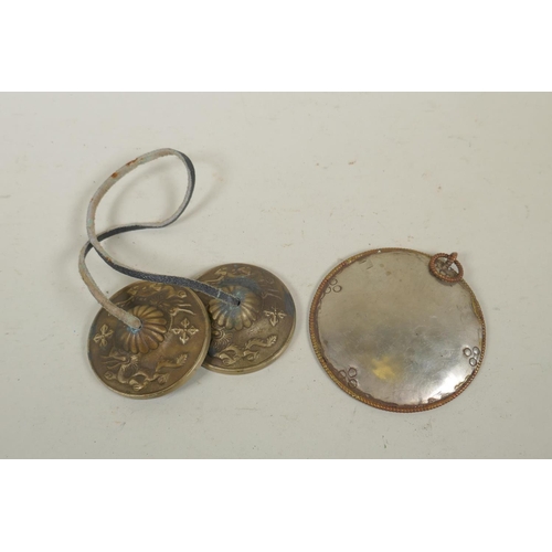 255 - A pair of Tibetan brass cymbals and a white metal mirror pendant, 10cm diameter