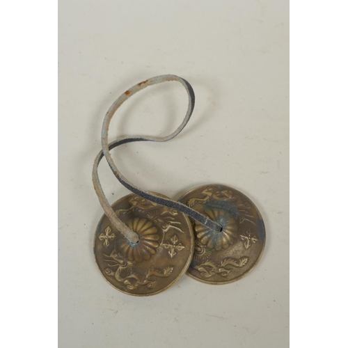 255 - A pair of Tibetan brass cymbals and a white metal mirror pendant, 10cm diameter