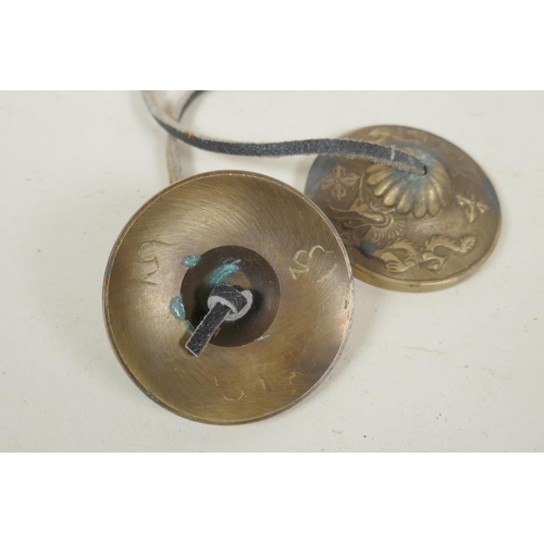 255 - A pair of Tibetan brass cymbals and a white metal mirror pendant, 10cm diameter