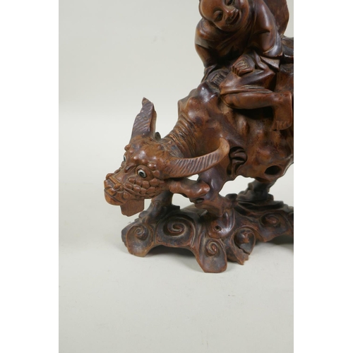 32 - An antique oriental carved root wood figure of a child riding a buffalo, 25cm high