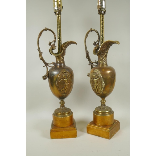 52 - Pair of brass ewer shaped table lamps with raised putti decoration, 74cm high