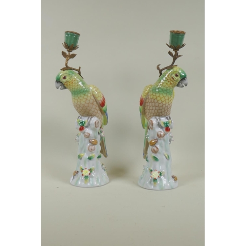 62 - Pair of porcelain and brass mounted candlesticks in the form of parrots, 36cm high