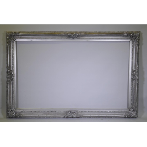 904 - A large silver coloured mirror/picture frame with composition moulded decoration, 153 x 223cm, rebat... 