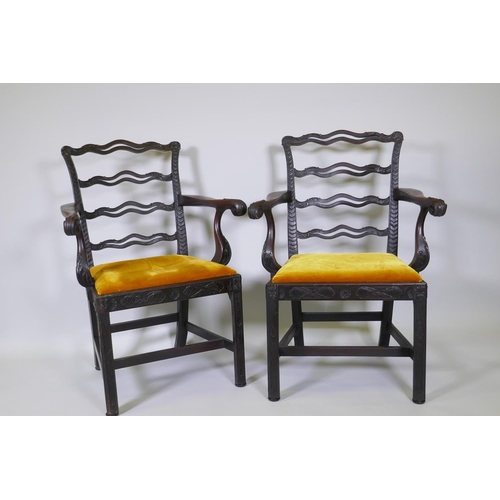 1005 - A pair of Chippendale style mahogany elbow chairs with pierced ladder backs and carved arms and rail... 