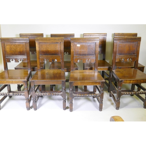 1031 - A set of eight William and Mary style panel backed oak chairs, with solid seats, raised on turned su... 