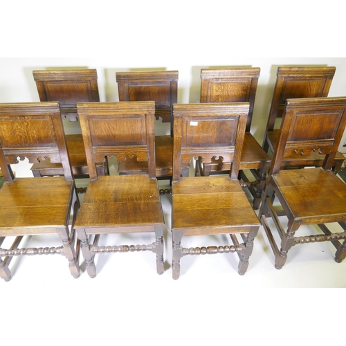 1031 - A set of eight William and Mary style panel backed oak chairs, with solid seats, raised on turned su... 