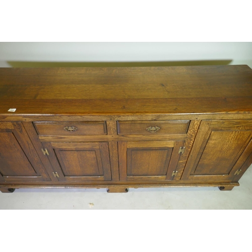 1034 - A Georgian style oak dresser with two drawers over two cupboards, flanked by two more, raised on bra... 