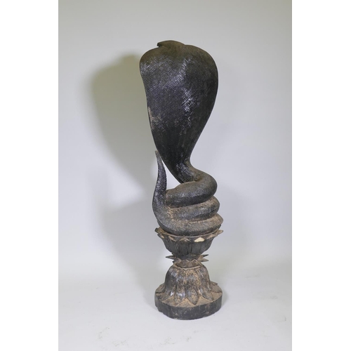 17 - A carved wood figure of a Cobra coiled upon a lotus dias, AF losses, 123cm high