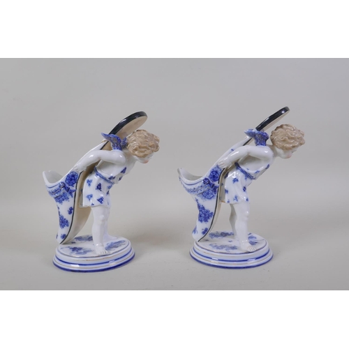 3 - A pair of early C20th continental porcelain posy holders/spoon warmers in the form of cherubs carryi... 