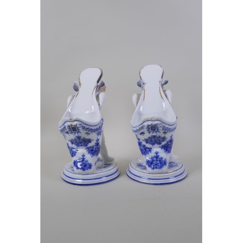 3 - A pair of early C20th continental porcelain posy holders/spoon warmers in the form of cherubs carryi... 