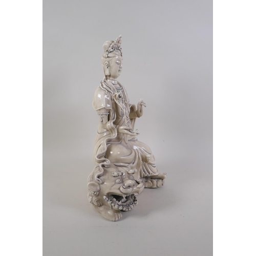 30 - A Chinese blanc de chine porcelain figure of Quanyin seated on a temple lion, impressed marks verso,... 