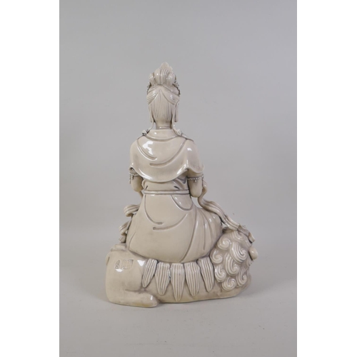 30 - A Chinese blanc de chine porcelain figure of Quanyin seated on a temple lion, impressed marks verso,... 