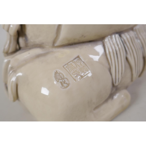 30 - A Chinese blanc de chine porcelain figure of Quanyin seated on a temple lion, impressed marks verso,... 