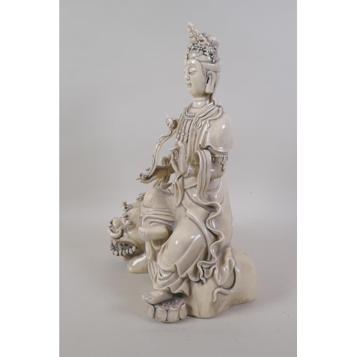 30 - A Chinese blanc de chine porcelain figure of Quanyin seated on a temple lion, impressed marks verso,... 