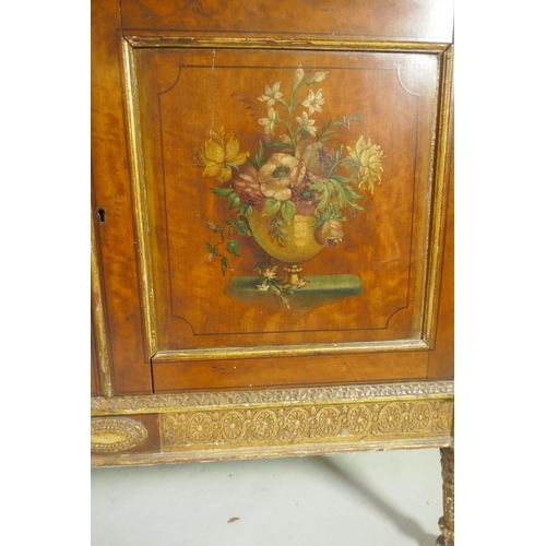 1001 - A C19th satinwood Sheraton Revival cabinet in two sections, with painted and parcel gilt decoration,... 