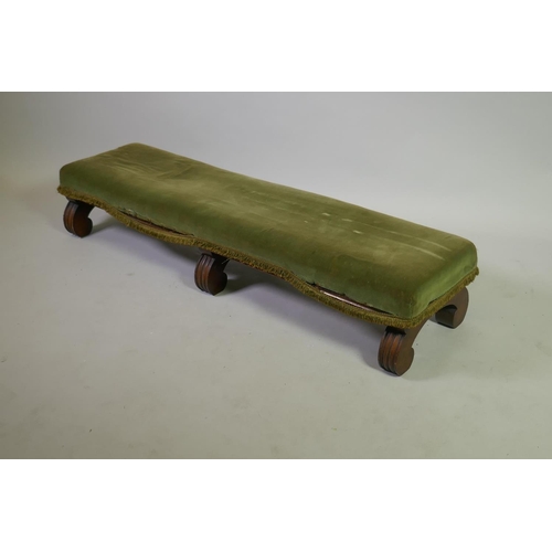 1034 - A C19th mahogany fender stool, raised on scroll supports, 125 x 34 x 24cm
