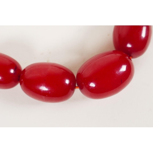 614 - A vintage graduated cherry amber necklace, 82cm long, 81g