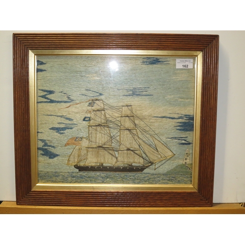 162 - A 19TH CENTURY SAILOR'S SILKWORK PICTURE depicting a fully rigged frigate with red ensign sailing of... 