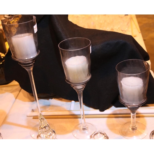 302 - Set of three amethyst coloured glass graduated glass candle holders, tallest H: 70 cm. Not available... 