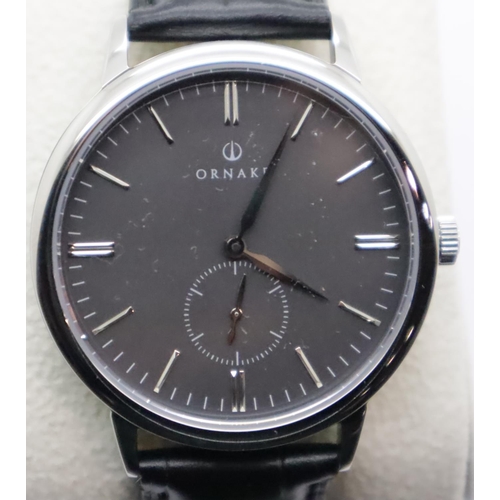 1068A - New old stock black faced silver gents Ornake wristwatch on black leather strap. P&P Group 1 (£14+VA... 