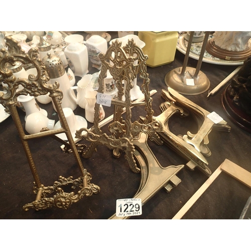 1229 - Three brass easel picture/book stands with a colletion of brass plate stands. Not available for in-h... 