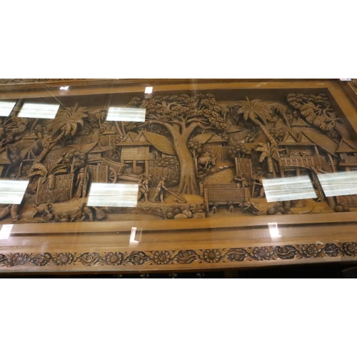 500 - A deeply carved substantial Oriental hardwood dining table with plate glass top displaying figures a... 