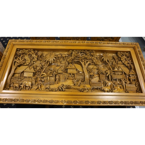 500 - A deeply carved substantial Oriental hardwood dining table with plate glass top displaying figures a... 