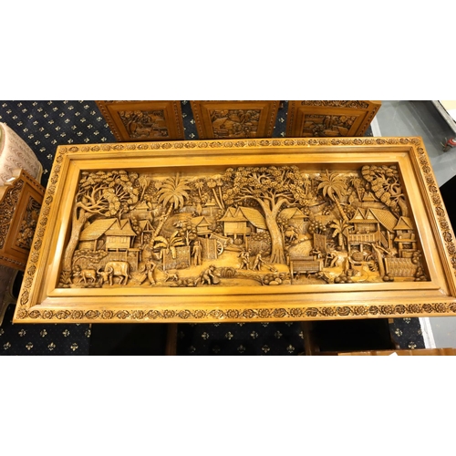 500 - A deeply carved substantial Oriental hardwood dining table with plate glass top displaying figures a... 