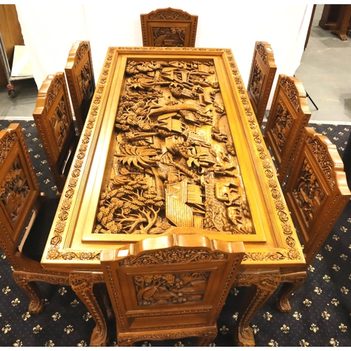 500 - A deeply carved substantial Oriental hardwood dining table with plate glass top displaying figures a... 