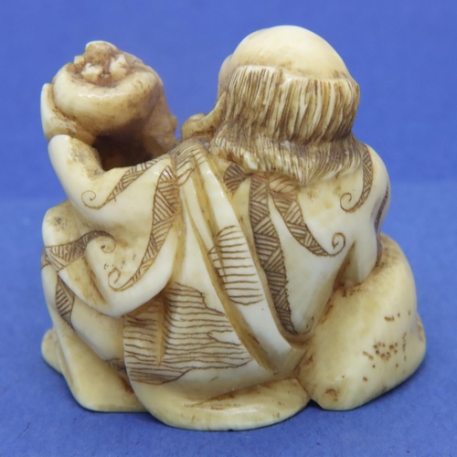 234 - Ivory carved netsuke in the form of a seated street vendor holding a fly whisk, H: 36 mm, signed to ... 