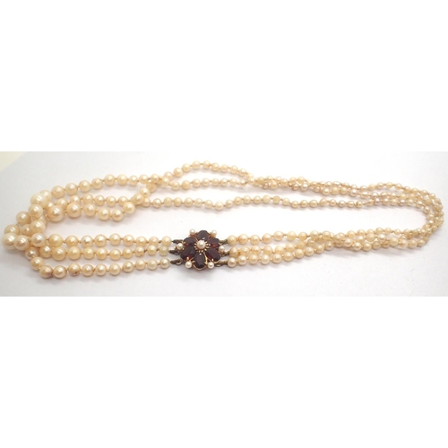 62 - Triple string pearl necklace with a large 9ct gold and garnet clasp, L: 45 cm, 31.0g, some pearlesce... 