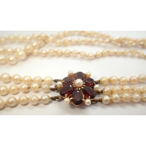 62 - Triple string pearl necklace with a large 9ct gold and garnet clasp, L: 45 cm, 31.0g, some pearlesce... 