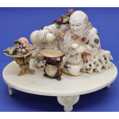 392 - Carved ivory of a seated gentleman with a toad on his head pouring Saki with a fruit table and a toa... 