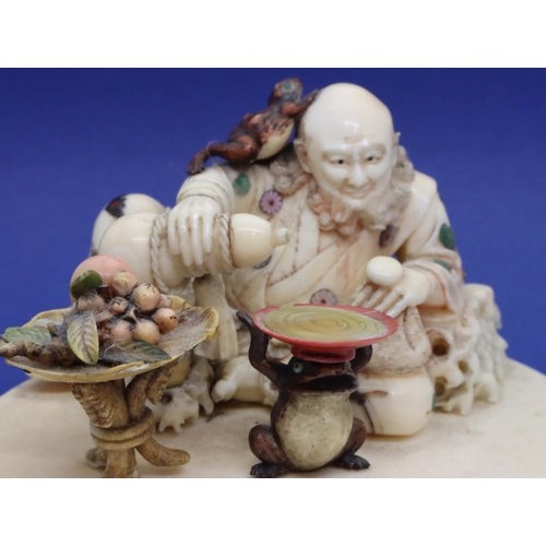 392 - Carved ivory of a seated gentleman with a toad on his head pouring Saki with a fruit table and a toa... 