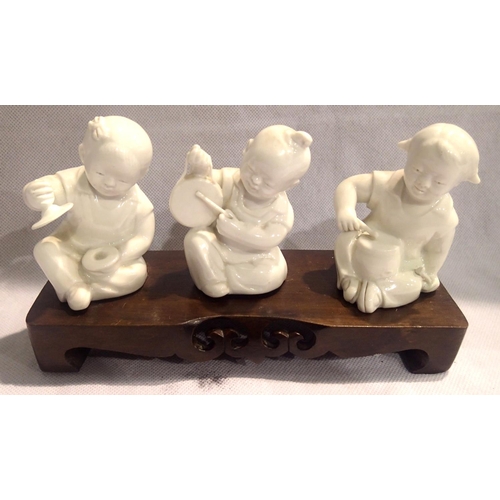 379 - Three Oriental ceramic musician figurines on a wooden base, each H: 11 cm. P&P Group 2 (£18+VAT for ... 