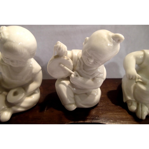 379 - Three Oriental ceramic musician figurines on a wooden base, each H: 11 cm. P&P Group 2 (£18+VAT for ... 