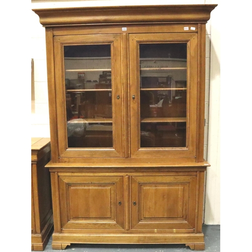 3103 - A substantial fruitwood bookcase with glazed doors enclosing adjustable shelves and drawers raised o... 