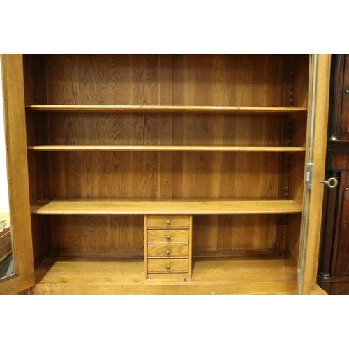 3103 - A substantial fruitwood bookcase with glazed doors enclosing adjustable shelves and drawers raised o... 