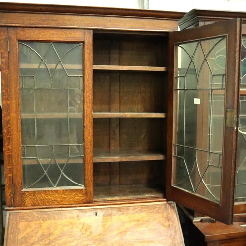 3154 - A late 19th century oak bureau bookcase, having two leaded glazed doors above a fitted interior and ... 