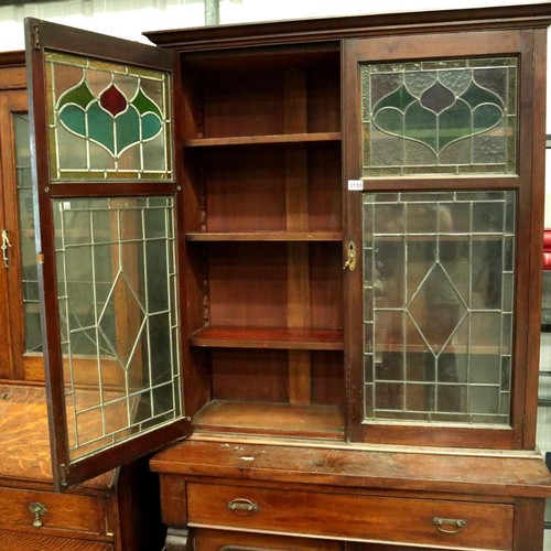 3155 - A Victorian bookcase, having two doors glazed with stained glass, three shelves raised above a sideb... 