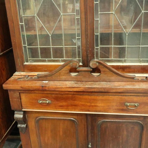 3155 - A Victorian bookcase, having two doors glazed with stained glass, three shelves raised above a sideb... 