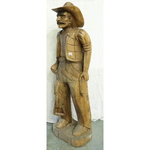 388 - Large carved wood cowboy figure with Lee belt buckle, H: 180 cm. Two cracks to hat, small crack wher... 