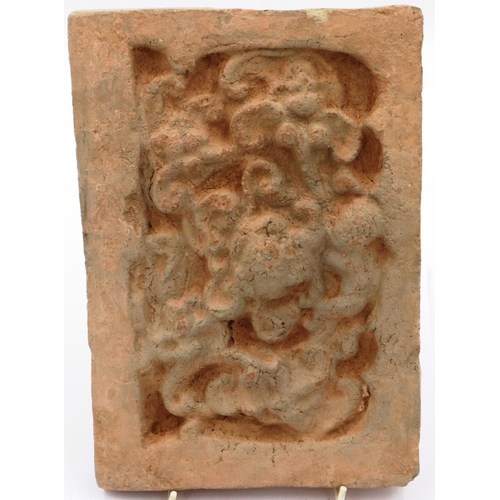 3006 - A Song Dynasty red clay tile, decorated in relief with a stylised front-facing dragon, 18 x 26 cm. P... 