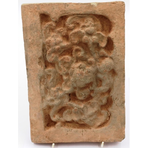 3006 - A Song Dynasty red clay tile, decorated in relief with a stylised front-facing dragon, 18 x 26 cm. P... 