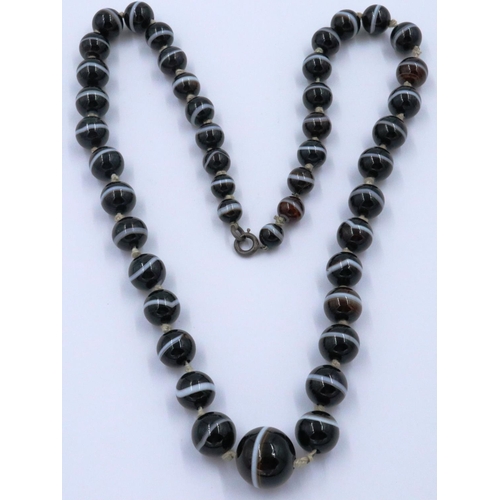 3070 - A single strand of graduated and polished brown manao agate beads formed as a necklace with knotted ... 