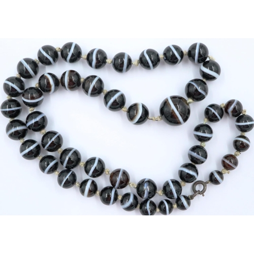 3070 - A single strand of graduated and polished brown manao agate beads formed as a necklace with knotted ... 