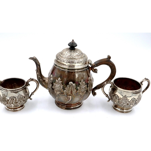 67 - A hallmarked silver three piece tea service, repousse decorated with flora and swags, London assay, ... 