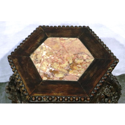 3090 - A padouk wood profusely carved vase stand, the top inset with a hexagonal panel of rouge marble, the... 