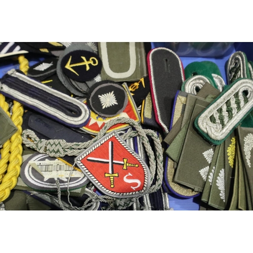 2080 - A large quantity of East German DDR uniform components, including epaulettes, lanyards, division pat... 