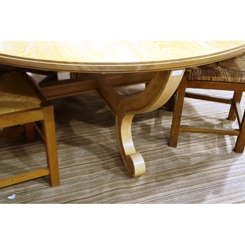 2098 - A substantial circular golden oak dining or breakfast table on a shaped quadripartide support and fo... 